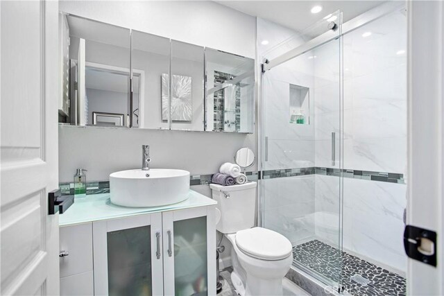 bathroom with a shower with door, vanity, and toilet