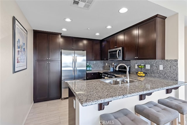 kitchen featuring appliances with stainless steel finishes, kitchen peninsula, sink, and backsplash