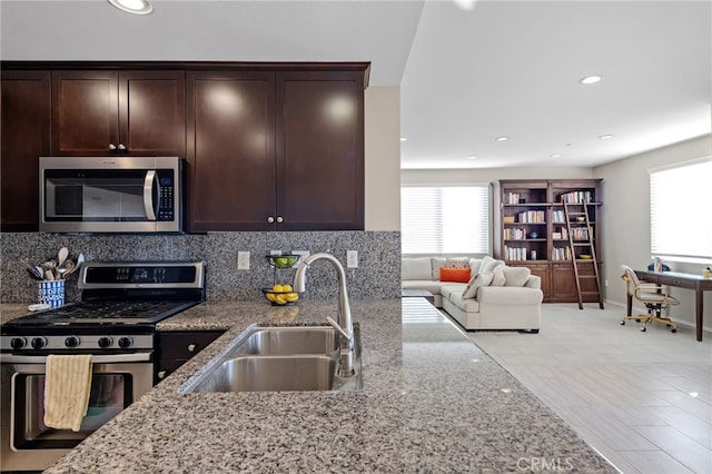 kitchen with stainless steel appliances, light stone countertops, sink, and a wealth of natural light