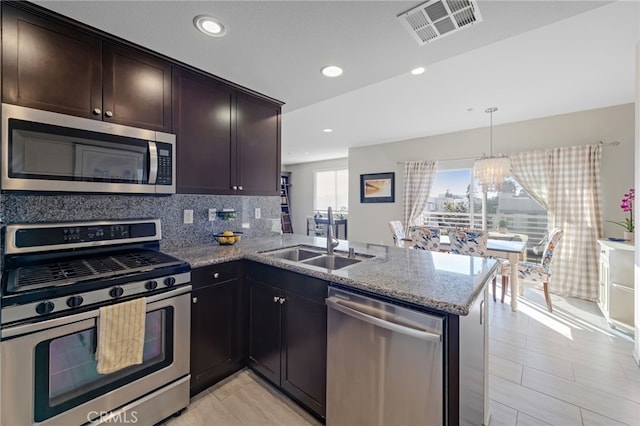 kitchen with sink, decorative light fixtures, kitchen peninsula, and appliances with stainless steel finishes