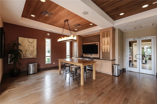 dining space featuring wood ceiling, hardwood / wood-style floors, a tray ceiling, french doors, and beverage cooler