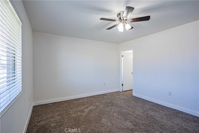 spare room featuring ceiling fan and dark colored carpet