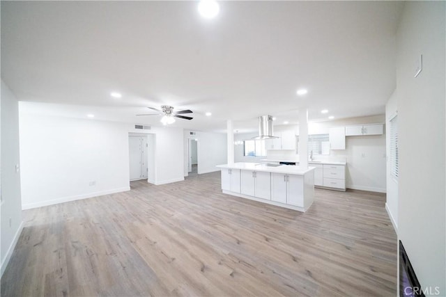 kitchen with island range hood, white cabinetry, a center island, ceiling fan, and light wood-type flooring