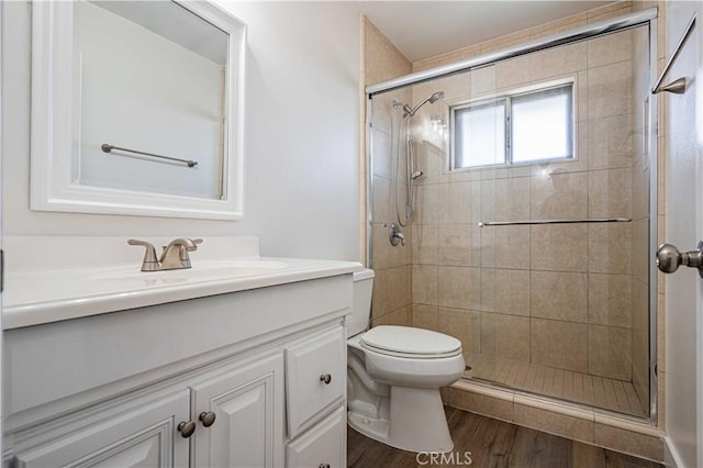 bathroom with hardwood / wood-style flooring, vanity, an enclosed shower, and toilet