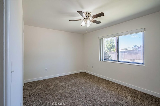 spare room featuring ceiling fan and dark colored carpet