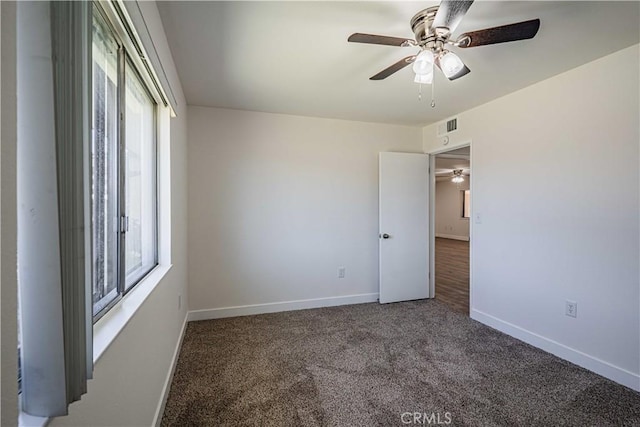 unfurnished room featuring dark colored carpet and ceiling fan