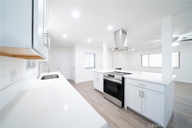 kitchen with white cabinetry, sink, stainless steel electric stove, and wall chimney exhaust hood