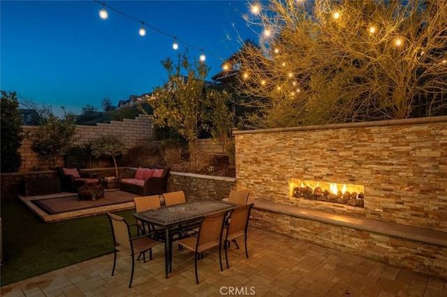 patio at night with an outdoor living space with a fireplace