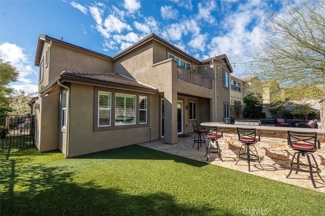 back of property with a patio, exterior bar, a yard, and a balcony