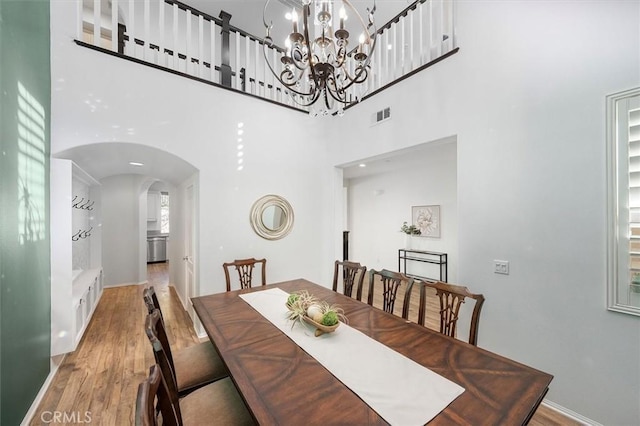 dining area featuring a chandelier, a high ceiling, and light wood-type flooring