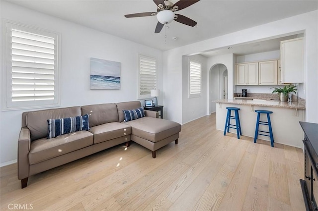 living room with plenty of natural light, ceiling fan, and light wood-type flooring