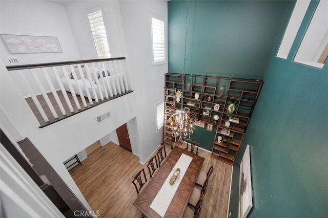 stairway featuring hardwood / wood-style flooring, a chandelier, and a towering ceiling