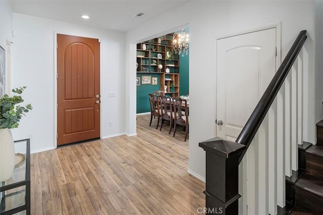 foyer entrance with an inviting chandelier and light hardwood / wood-style floors