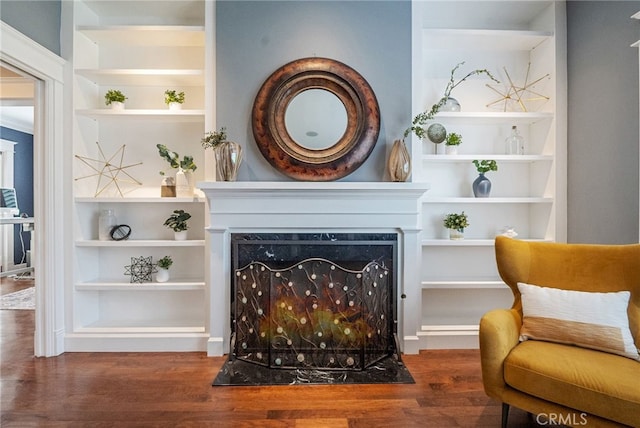 living area featuring dark hardwood / wood-style flooring, a high end fireplace, and built in features