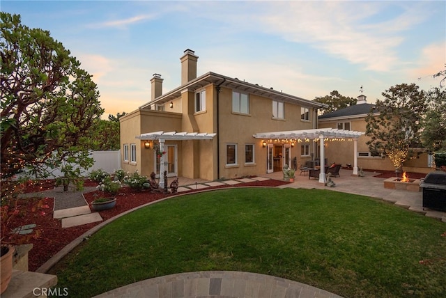 back house at dusk with a lawn, a patio area, and a pergola