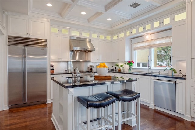 kitchen featuring wall chimney range hood, a breakfast bar area, white cabinetry, stainless steel appliances, and a center island