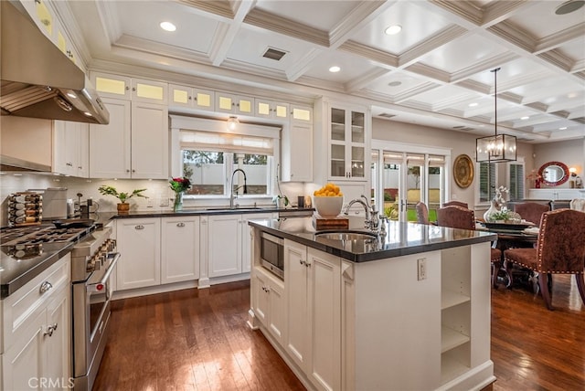 kitchen with white cabinetry, sink, extractor fan, and a center island with sink