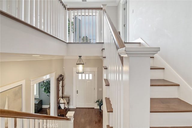 stairs with a high ceiling, wood-type flooring, a wealth of natural light, and crown molding