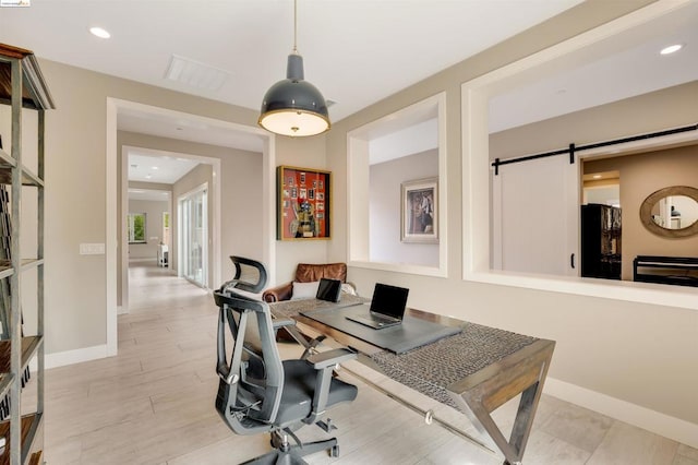 office area with a barn door and light wood-type flooring