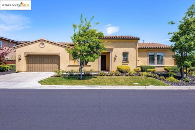 mediterranean / spanish-style house featuring a garage and a front lawn