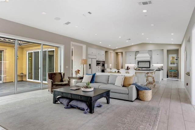 living room featuring plenty of natural light, vaulted ceiling, and light hardwood / wood-style flooring