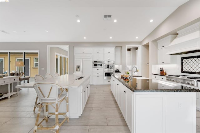 kitchen with sink, appliances with stainless steel finishes, dark stone counters, a large island, and decorative backsplash