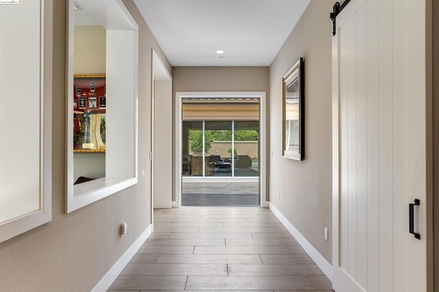 hall with wood-type flooring and a barn door