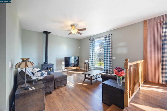 living room with hardwood / wood-style flooring, ceiling fan, and a wood stove