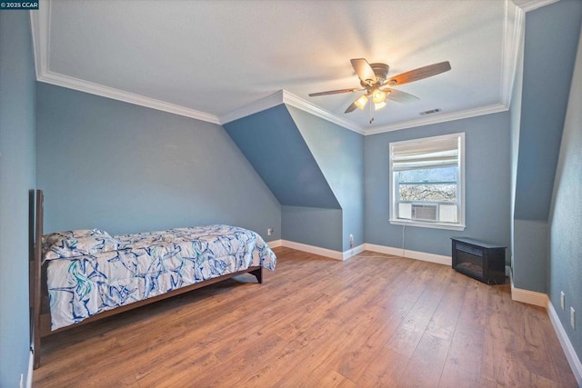 bedroom with lofted ceiling, crown molding, a wood stove, hardwood / wood-style flooring, and ceiling fan