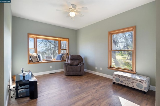 living area with ceiling fan and dark hardwood / wood-style floors