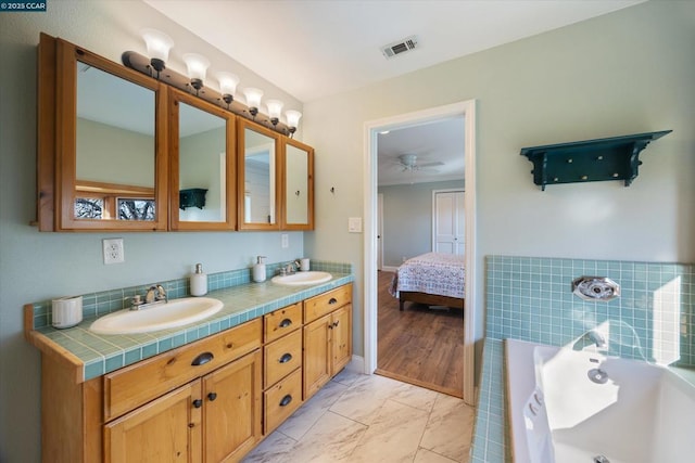 bathroom with ceiling fan, vanity, and a bathtub