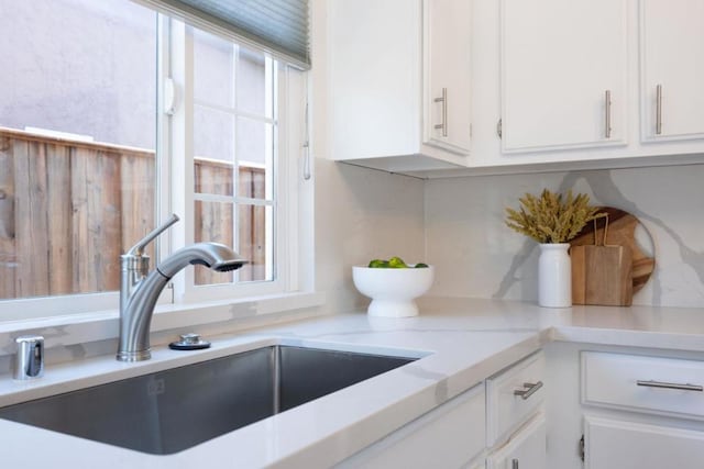 kitchen featuring white cabinetry, sink, a wealth of natural light, and tasteful backsplash