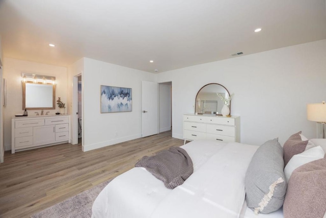 bedroom with ensuite bathroom, sink, and light hardwood / wood-style floors