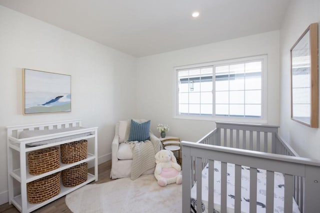 bedroom featuring hardwood / wood-style floors and a nursery area