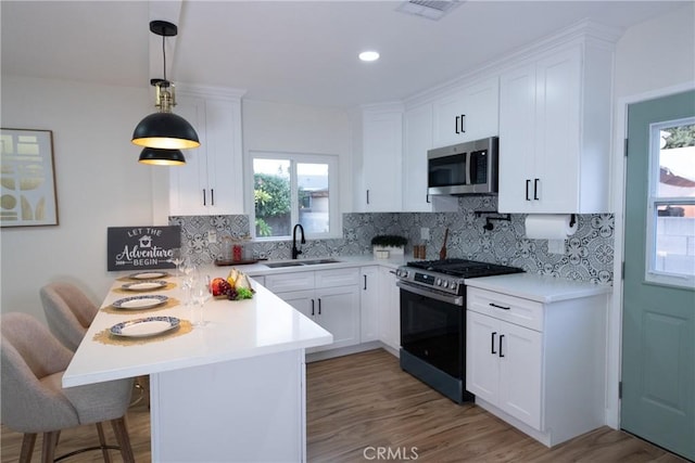 kitchen with stainless steel appliances, kitchen peninsula, sink, and white cabinets