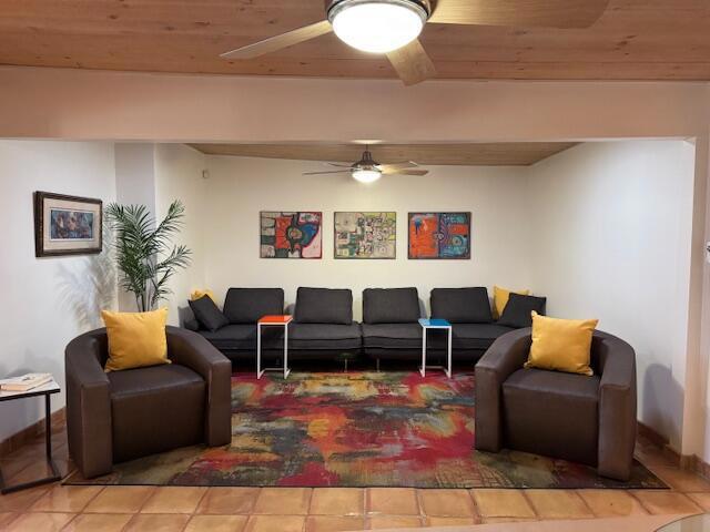 living room with tile patterned floors, wooden ceiling, and ceiling fan