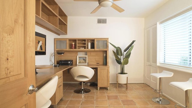 office area with built in desk, ceiling fan, and light tile patterned floors