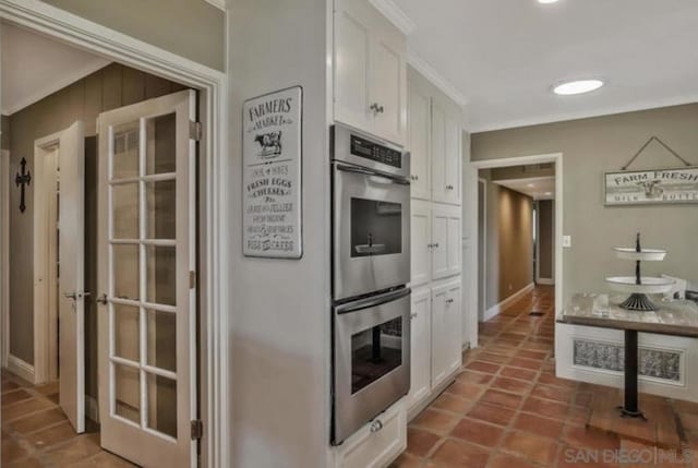 kitchen featuring double oven, crown molding, white cabinets, and dark tile patterned flooring