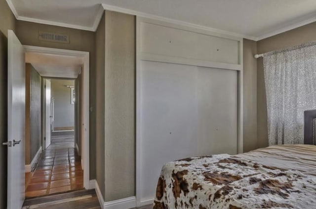 bedroom featuring crown molding, dark hardwood / wood-style floors, and a closet