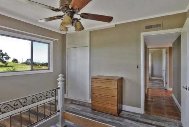 interior space with ornamental molding, dark wood-type flooring, ceiling fan, and a closet