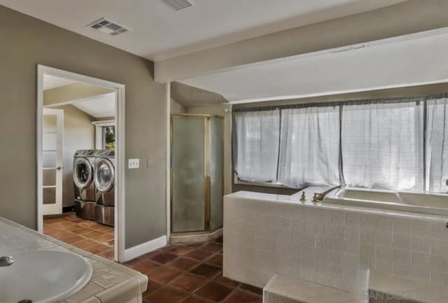 bathroom with tile patterned flooring, vaulted ceiling, washer and clothes dryer, and walk in shower