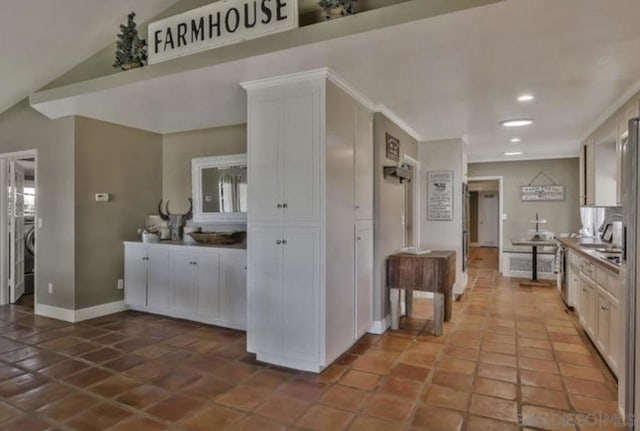 kitchen with white cabinetry, vaulted ceiling, sink, and dishwashing machine