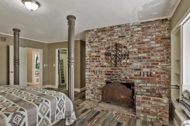 bedroom featuring hardwood / wood-style floors, crown molding, and a fireplace