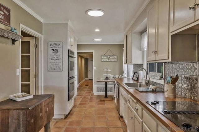 kitchen featuring sink, tasteful backsplash, light tile patterned floors, ornamental molding, and appliances with stainless steel finishes