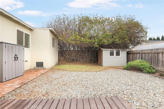 wooden terrace with cooling unit, a patio area, and a storage shed