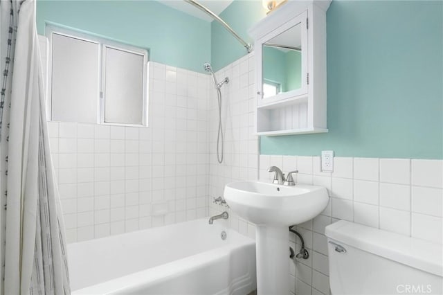 full bathroom featuring shower / bathtub combination with curtain, sink, tile walls, and toilet