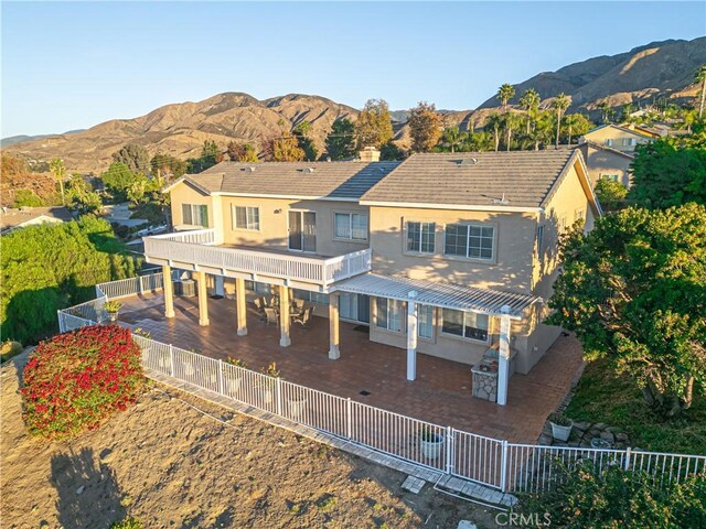 back of house featuring stucco siding, a fenced backyard, a mountain view, and a patio