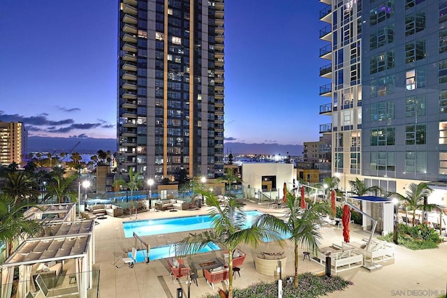 pool at dusk featuring a patio area