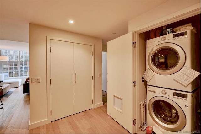 laundry area featuring light wood-type flooring and stacked washing maching and dryer