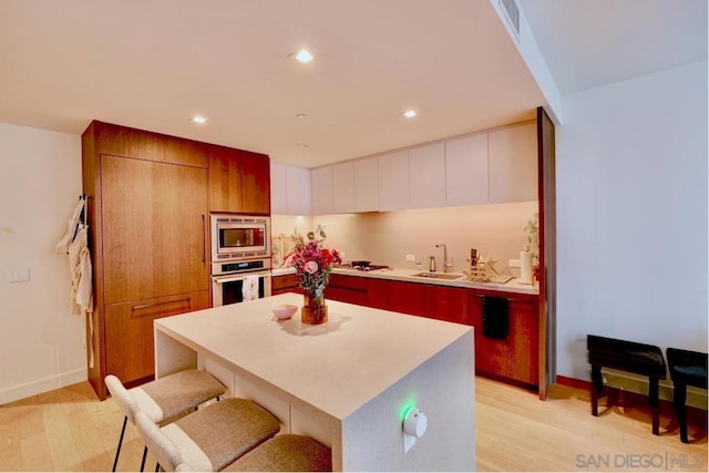 kitchen featuring appliances with stainless steel finishes, sink, a breakfast bar area, white cabinets, and a center island